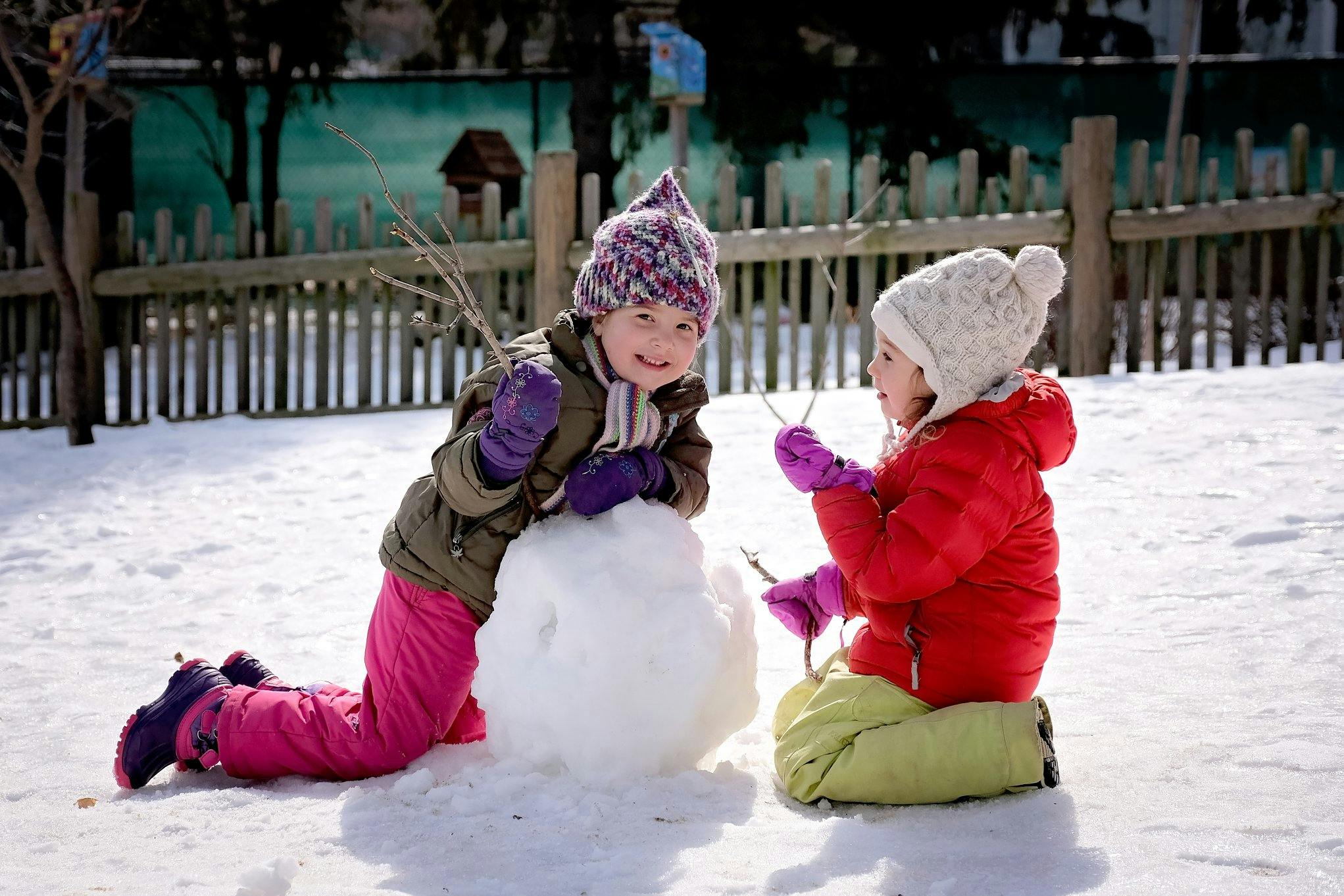 Two children building a snowman in the snow