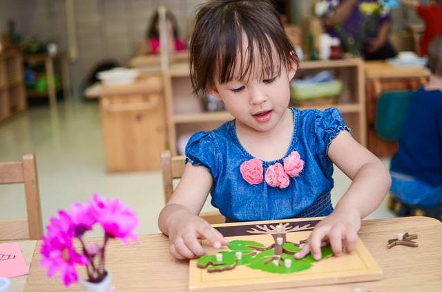 Child playing with a wooden puzzle on a table