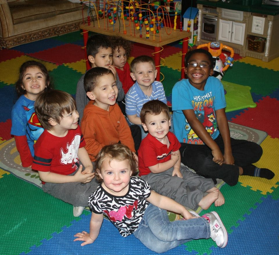 Group of children sitting on a colorful mat in a classroom