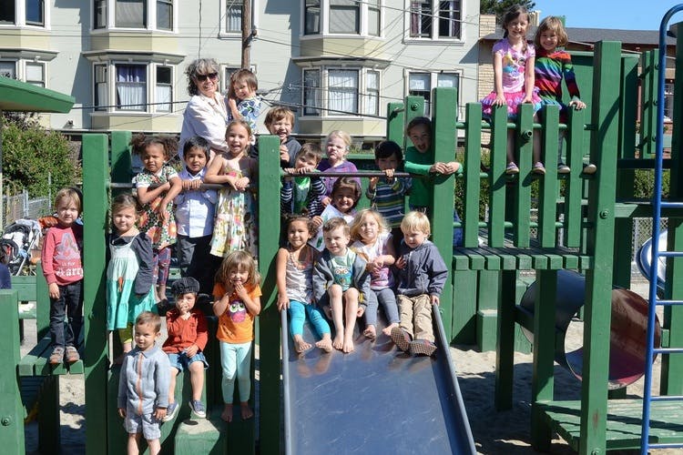 Adult and children on a playground structure with a slide