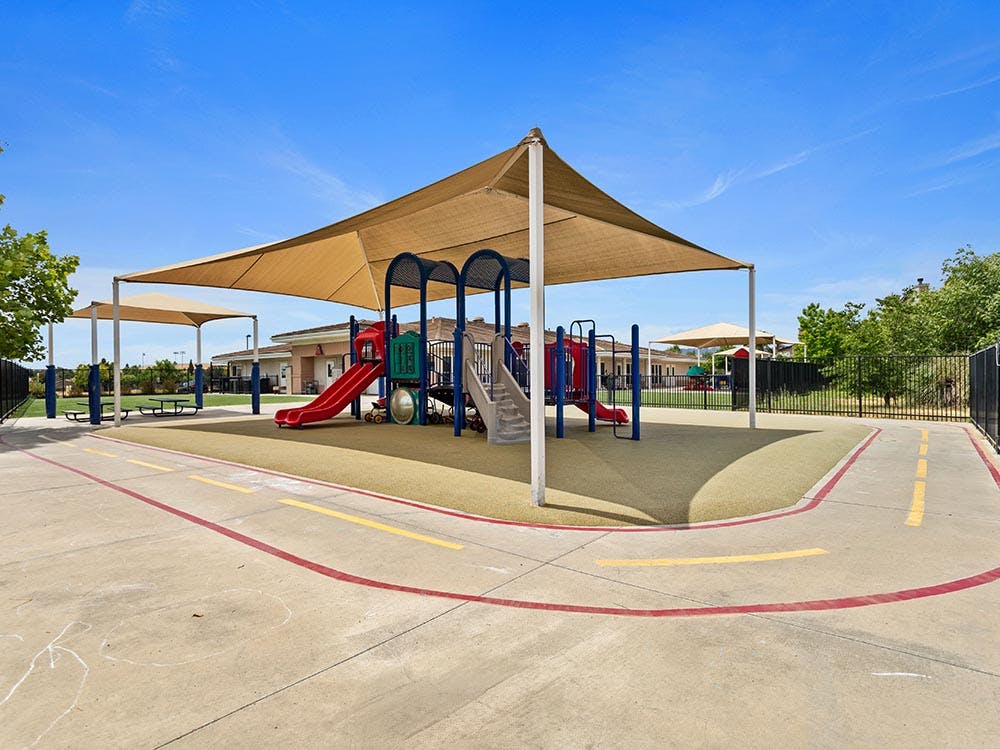 Playground with slides and climbing structure under a large shade sail
