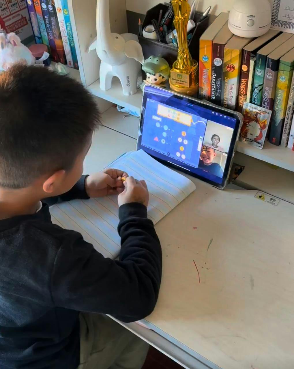 Child participating in an online video call on a tablet at a desk