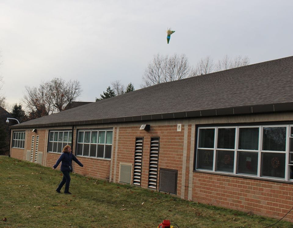 Child flying a kite near a building