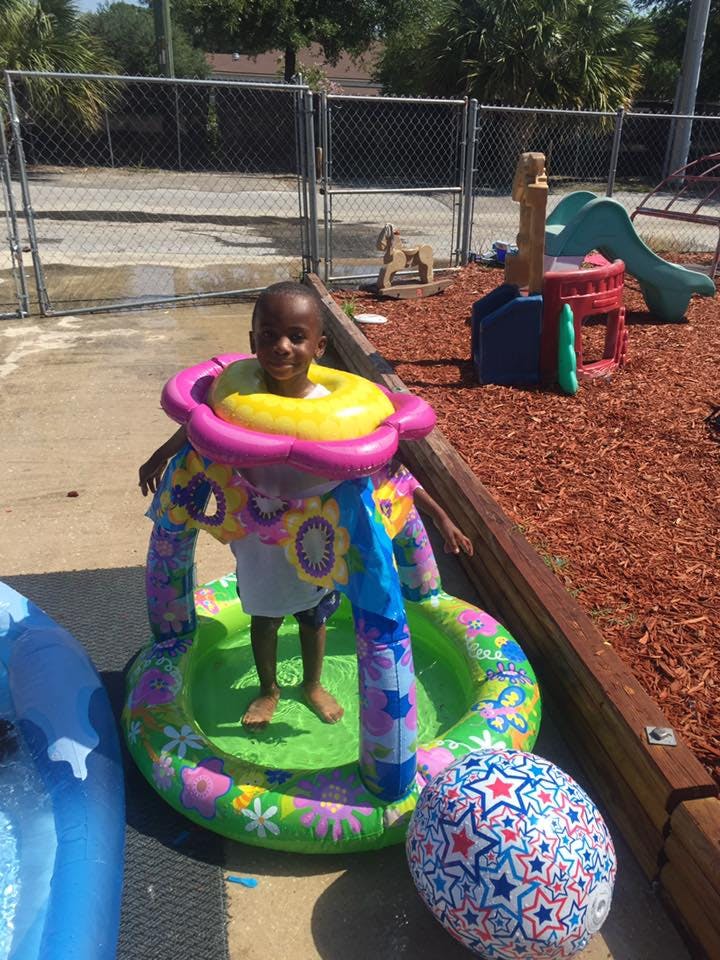 Child standing in an inflatable pool with a float around their neck