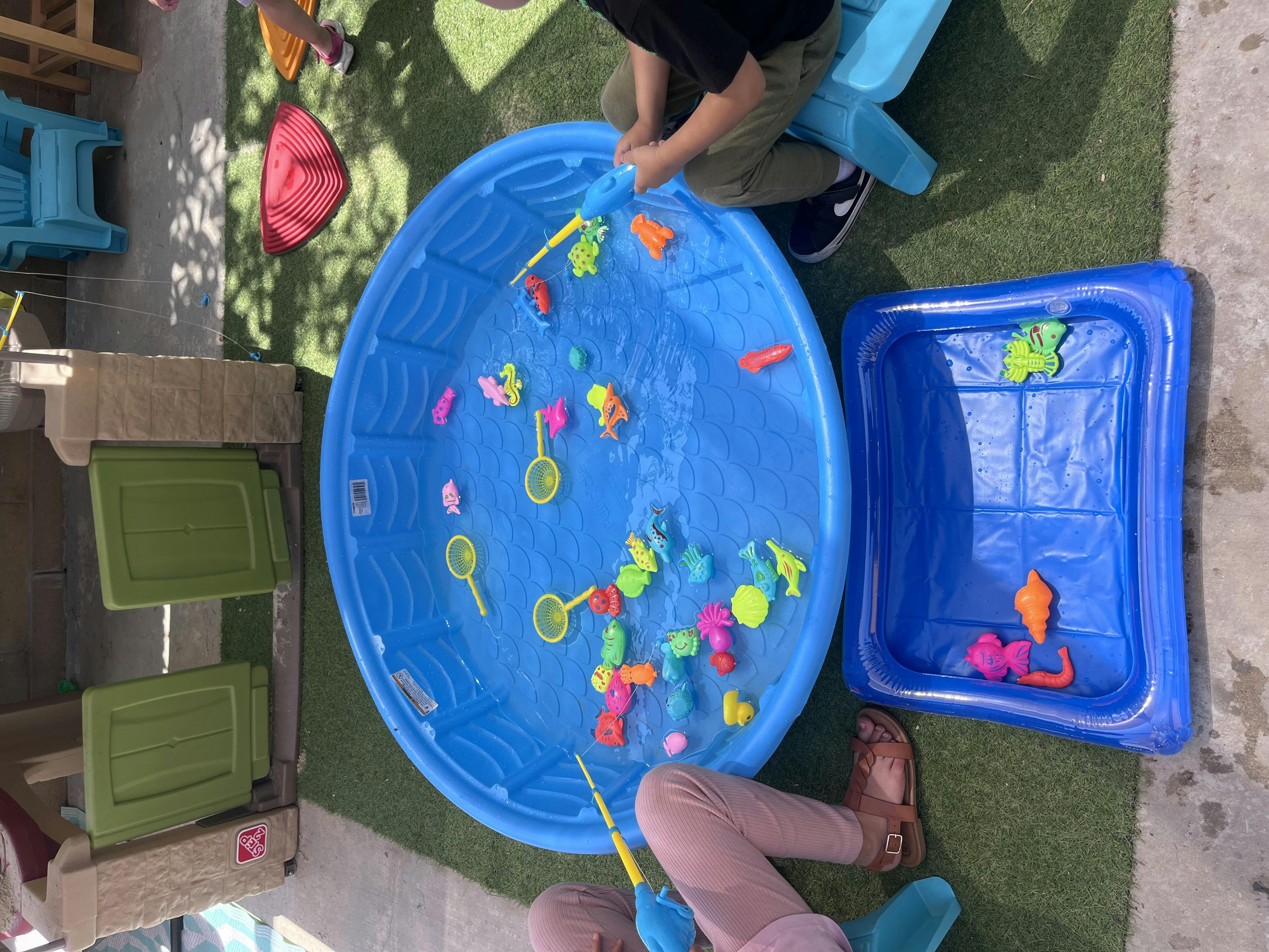 Two children playing with toys in blue water tubs