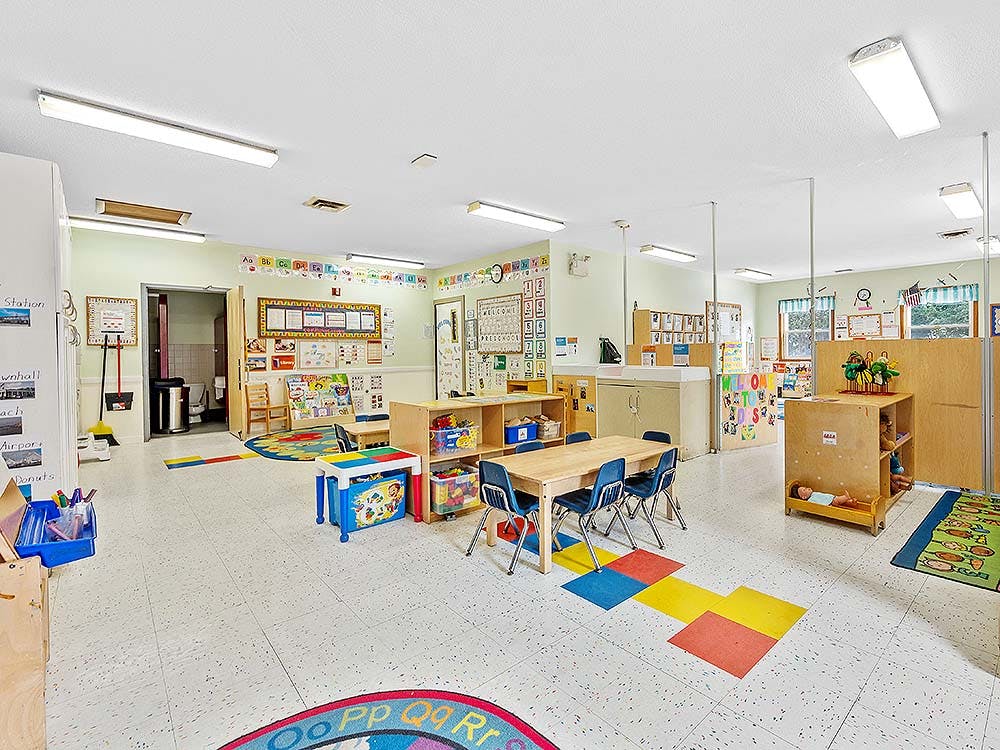 Empty colorful children's classroom with tables, chairs, and learning materials