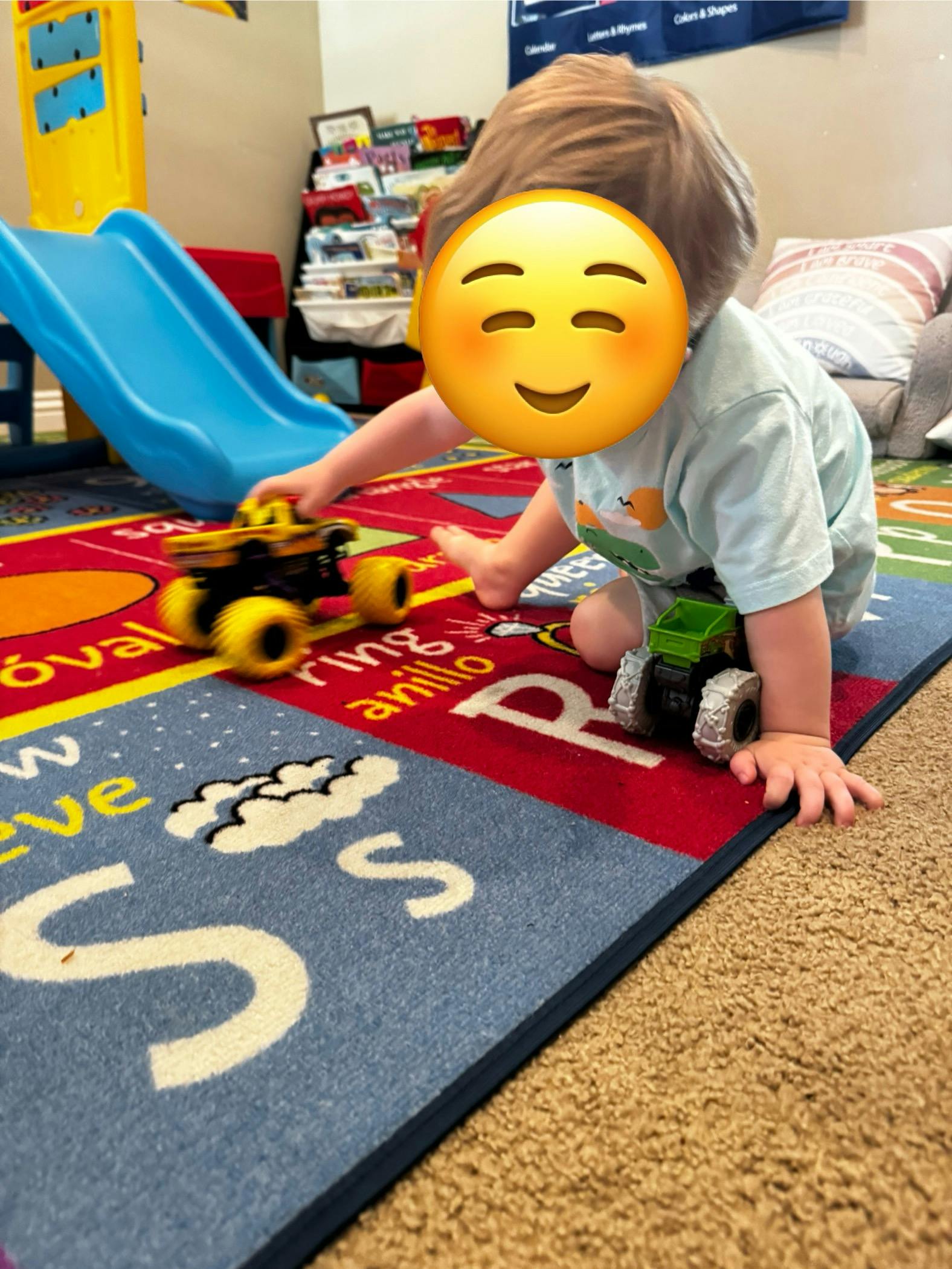 Child playing with toy monster trucks on a decorative floor mat