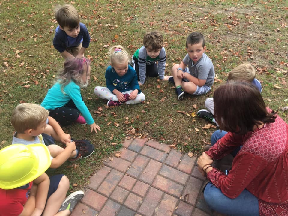 Adult and children sitting on grass in a circle