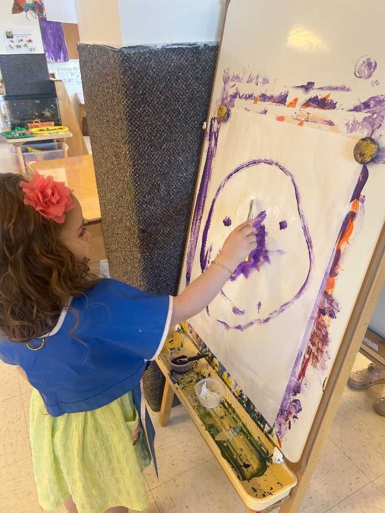 Child painting on paper attached to an easel
