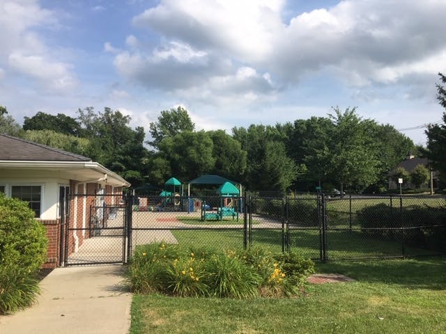 Playground equipment visible beyond a black chain-link fence