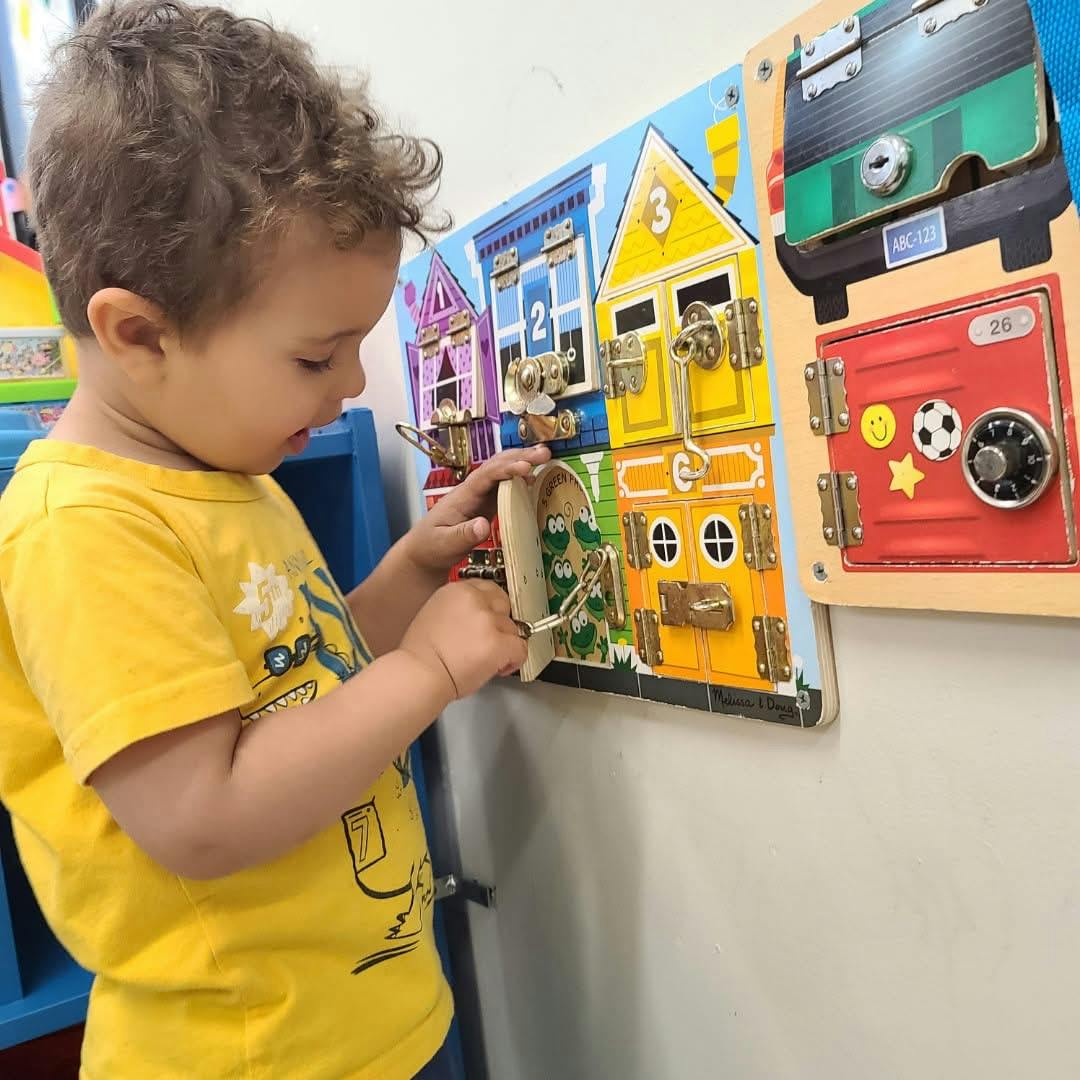 Child playing with a wooden latch board