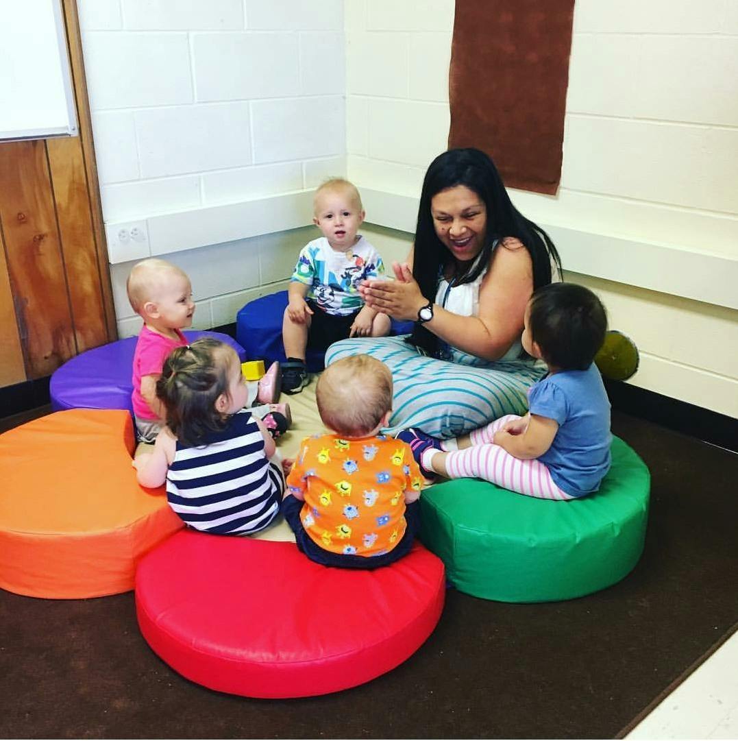 Adult person sitting on floor with four children in a circle