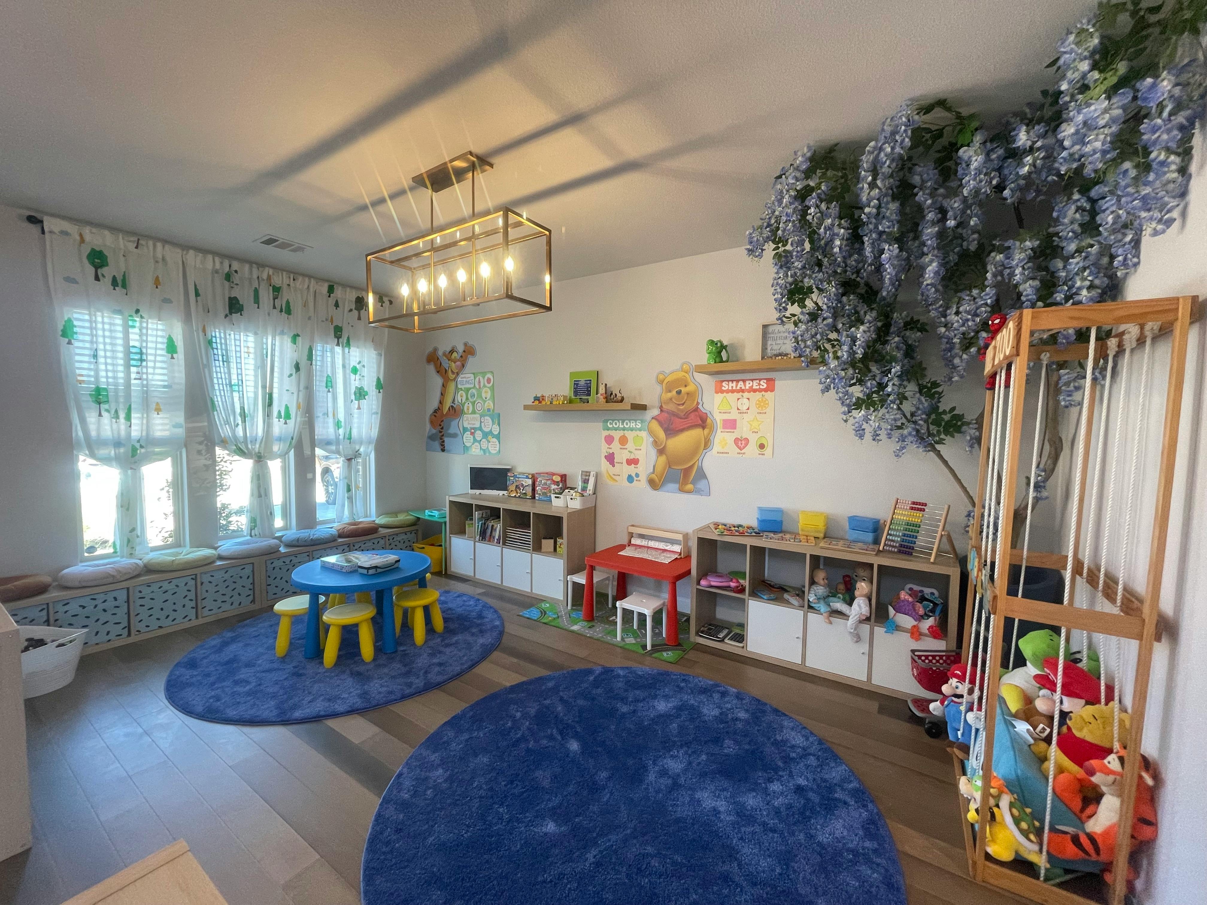 Playroom with small blue table and yellow chairs, blue rugs, and toy storage