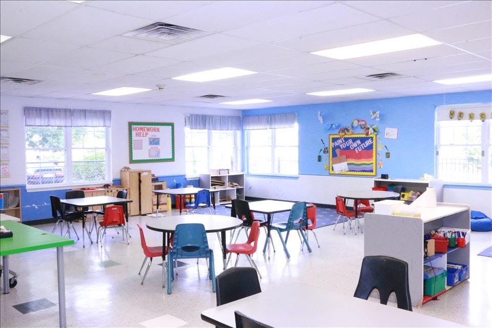 Classroom with tables and chairs, bulletin boards, and windows