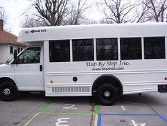 White shuttle bus with "Step By Step Inc" on the side