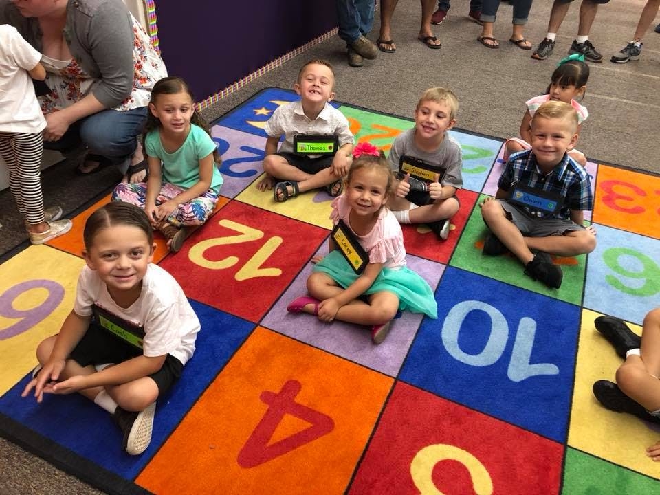 Children sitting on a colorful number rug