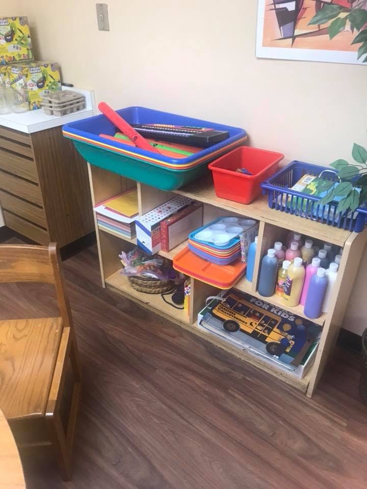 Shelving unit with various art supplies and containers in a classroom