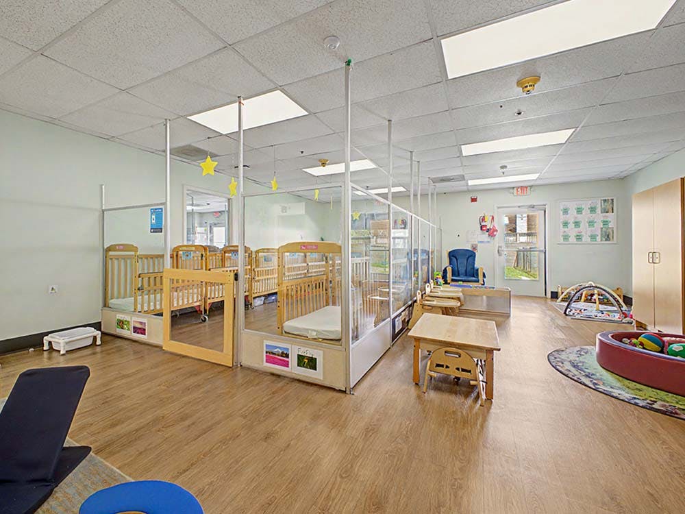 Cribs separated by clear partitions in a daycare or nursery room