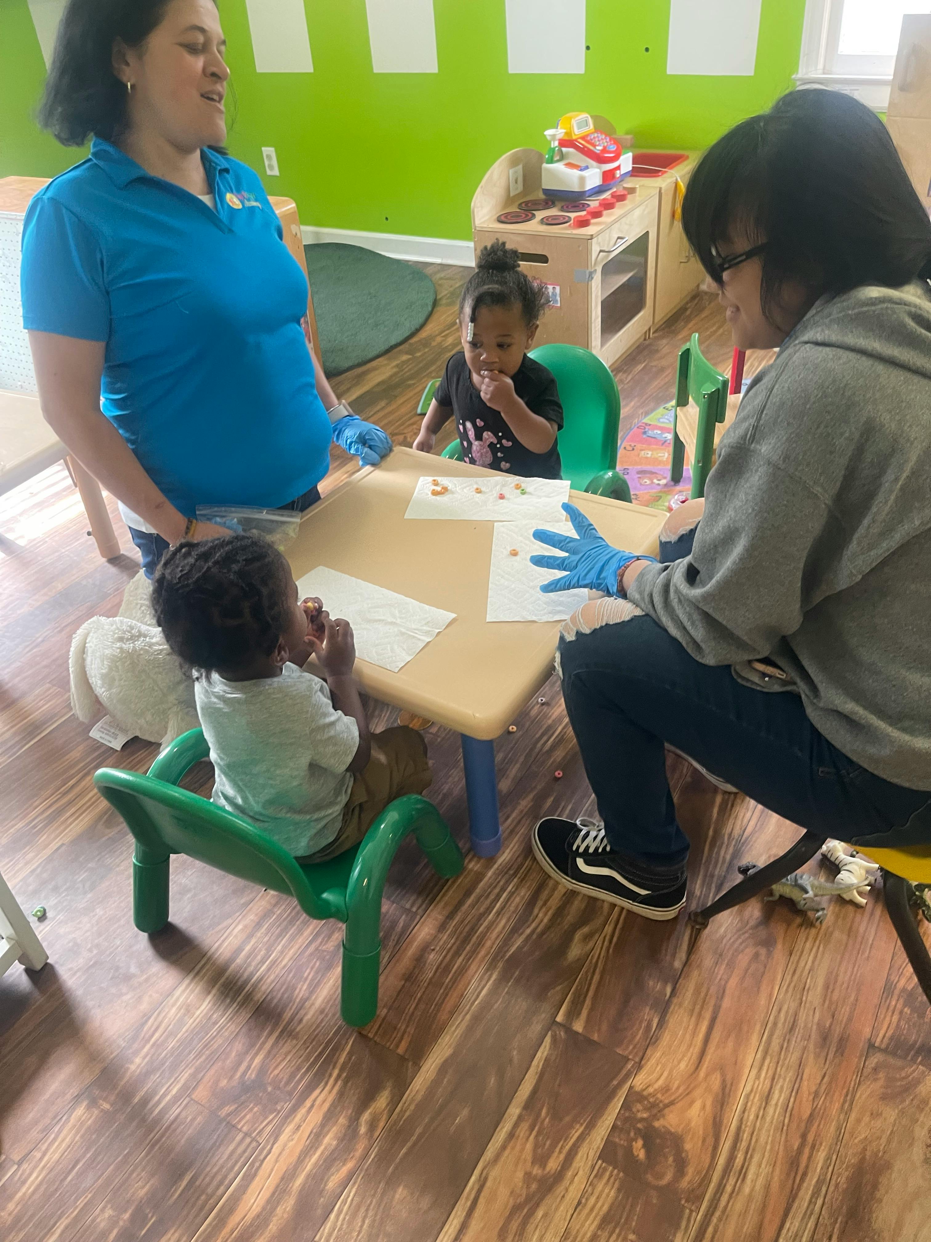 Two adults and two children at a small table in a classroom