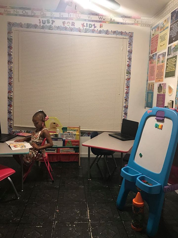 Child sitting at a desk reading a book in a classroom