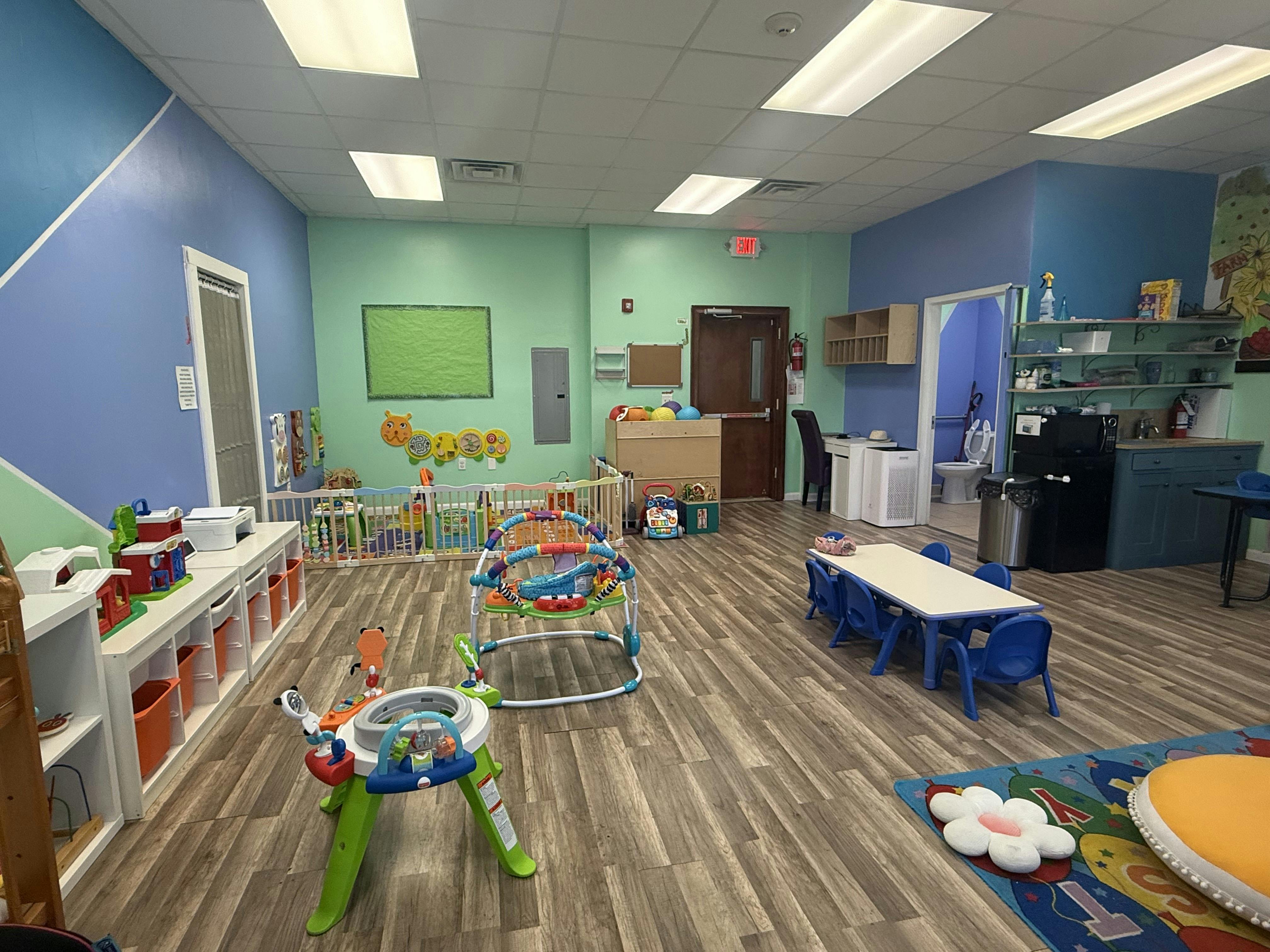 Spacious child care room with play equipment and small tables