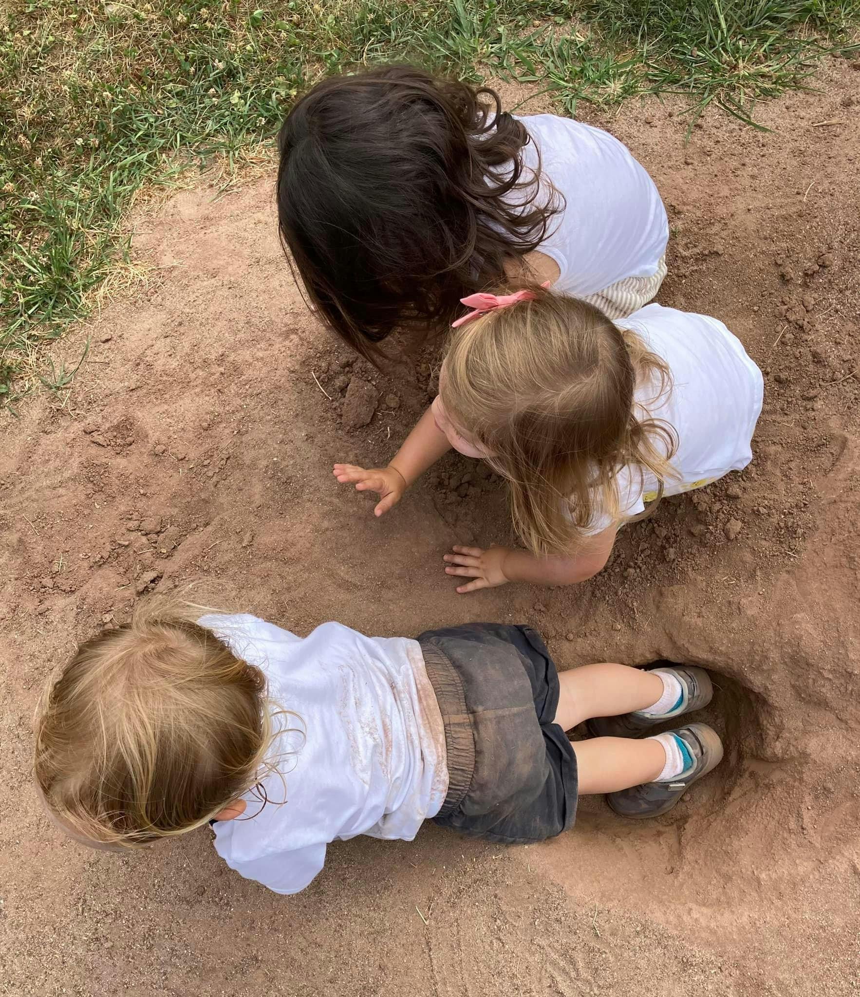 Three children playing in dirt