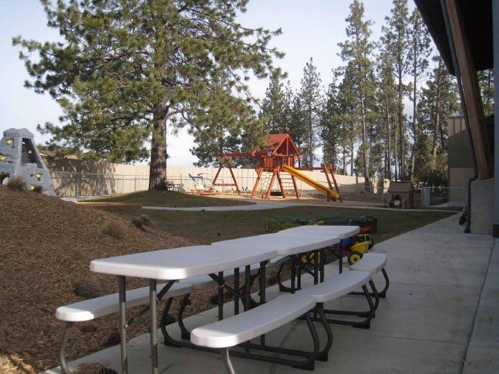 Picnic tables on a patio with a playground in the background