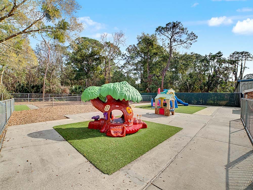Playground with a red and green tree-shaped playhouse and a colorful play structure