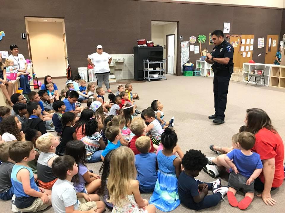 Police officer speaking to a group of children sitting on the floor
