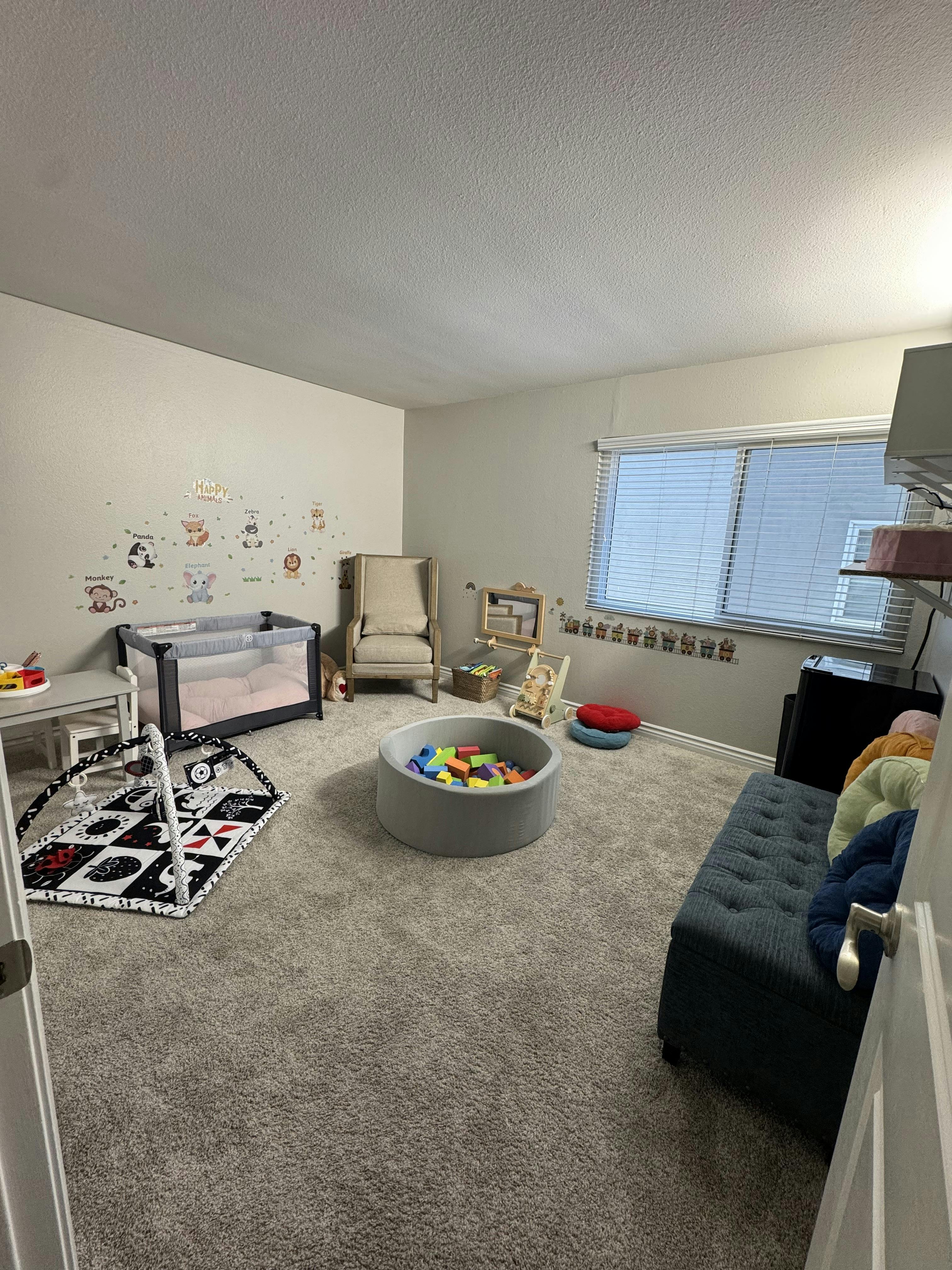 Child playroom with a playpen, foam ball pit, and activity mat