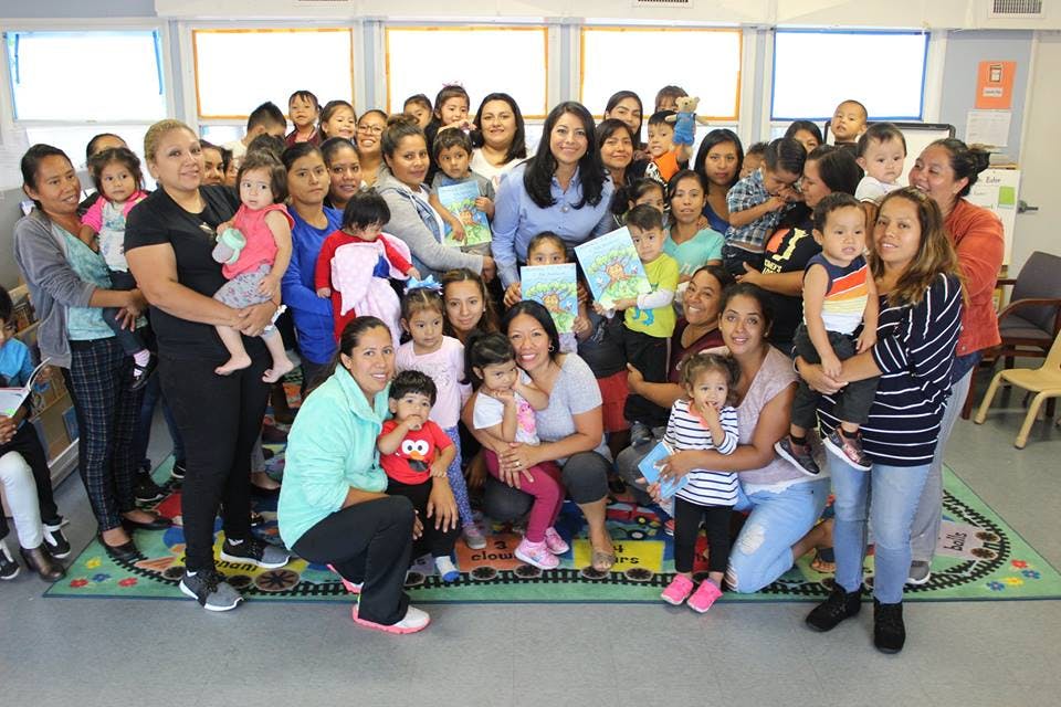 Group of adults and children posing for a photo in a classroom