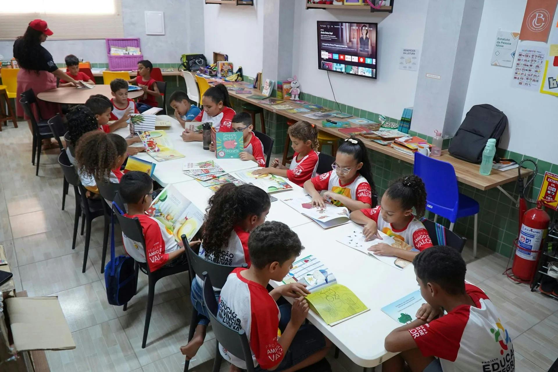 Group of children sitting at tables in a classroom reading books