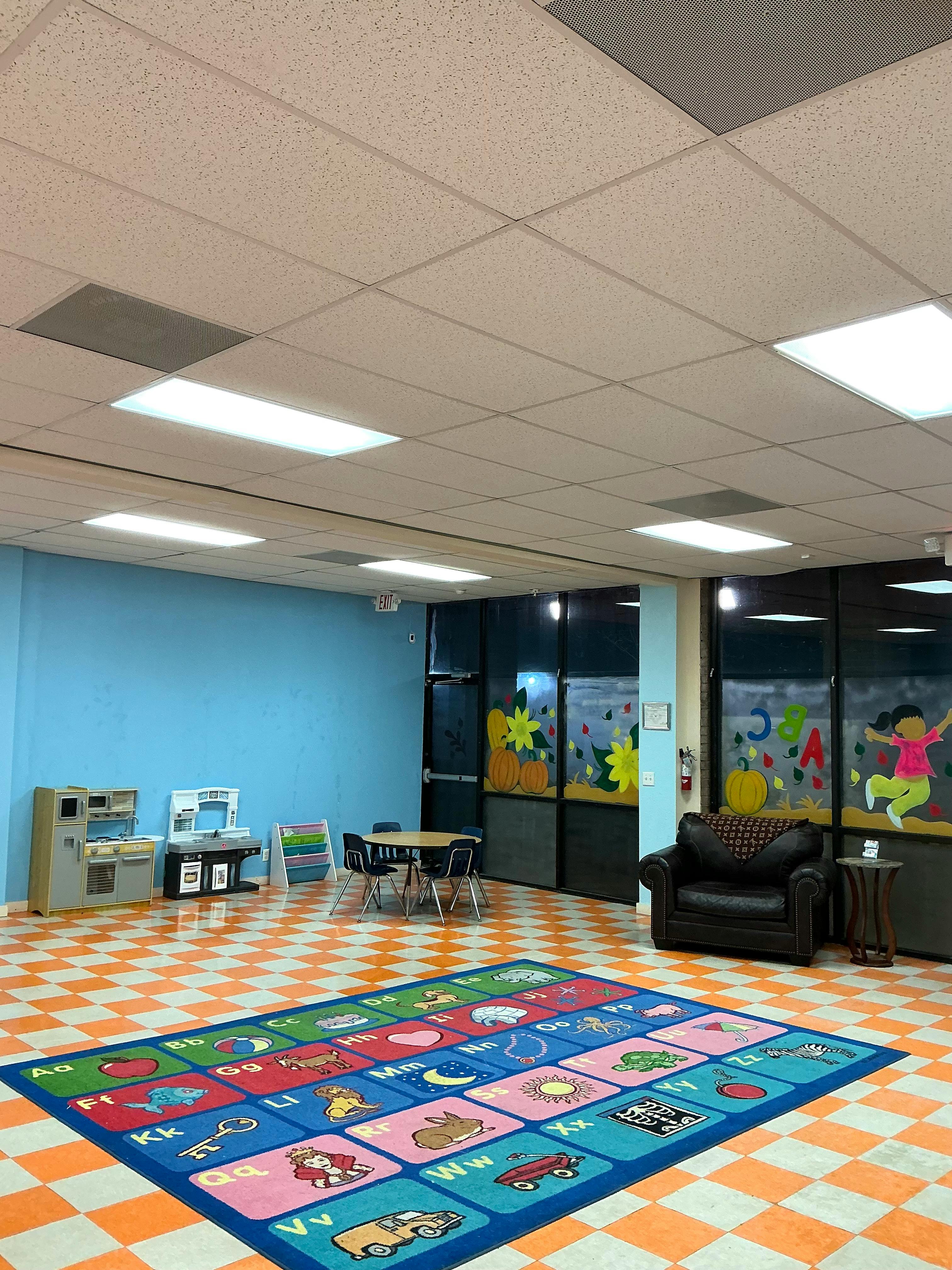 Playroom with alphabet rug, small table and chairs, and toy kitchen