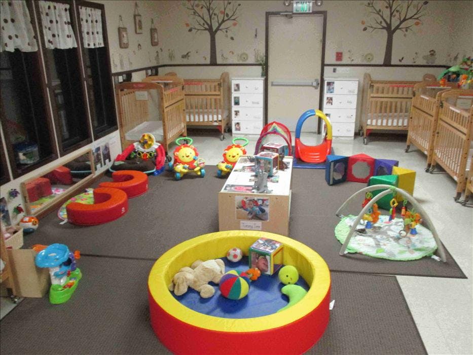 daycare or nursery room with cribs, play mats, and various colorful toys