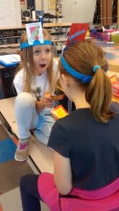 Child with a card on their head looking at another child