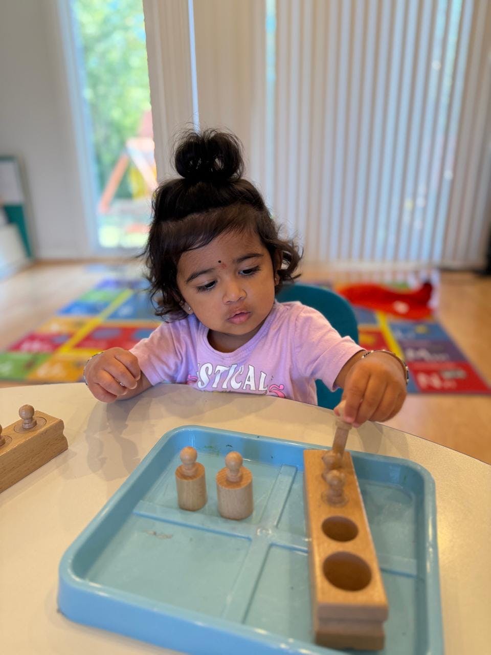 Child playing with wooden peg puzzle on a tray