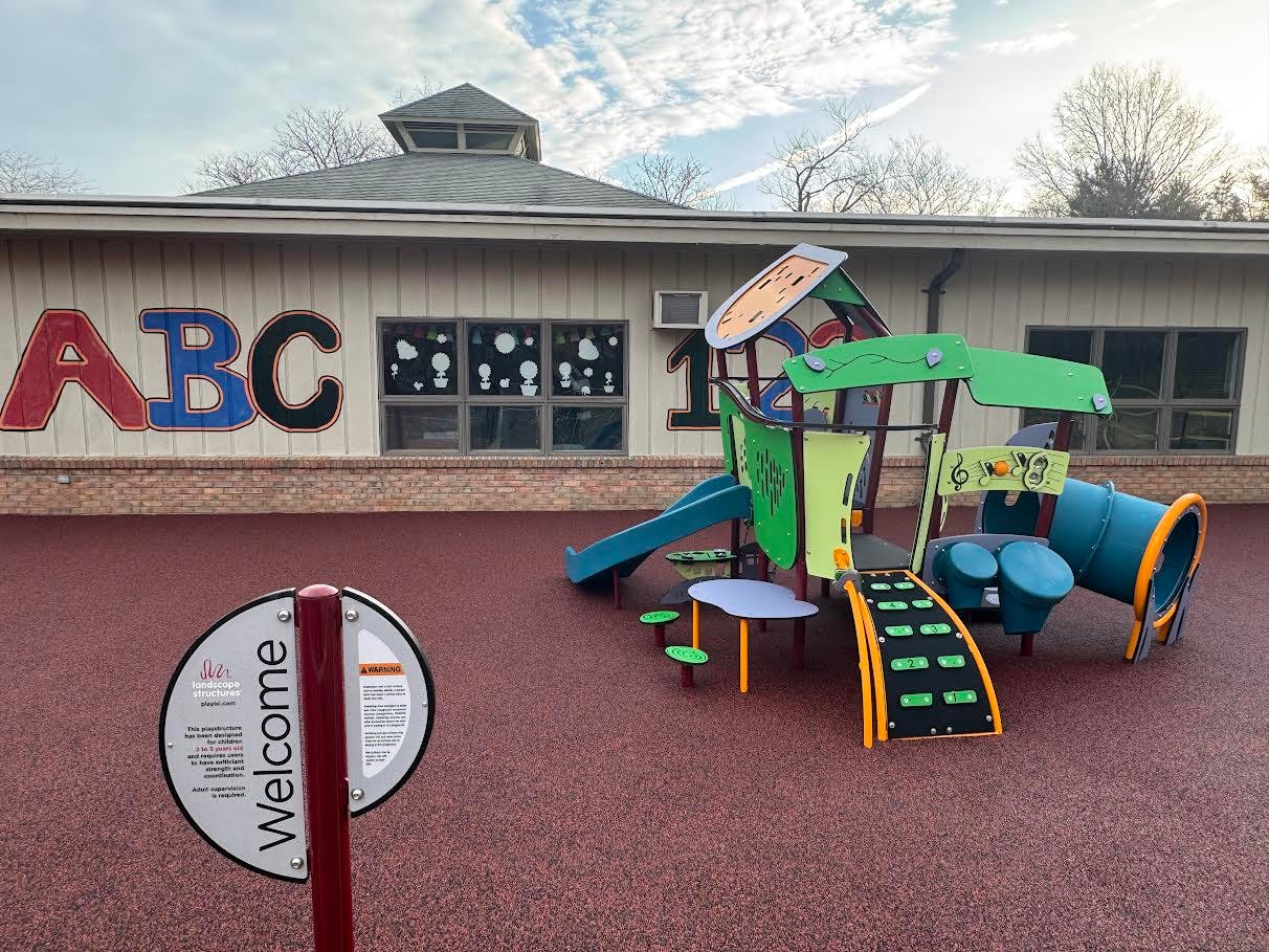 Playground with slides and climbing structures outside a building with ABC on it