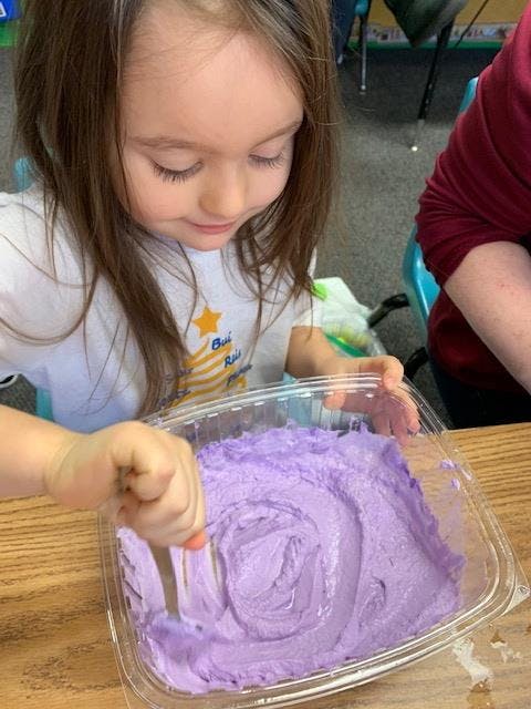 Child mixing purple substance in a clear container