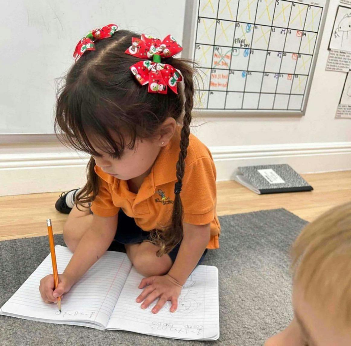 Child writing in a notebook with a pencil