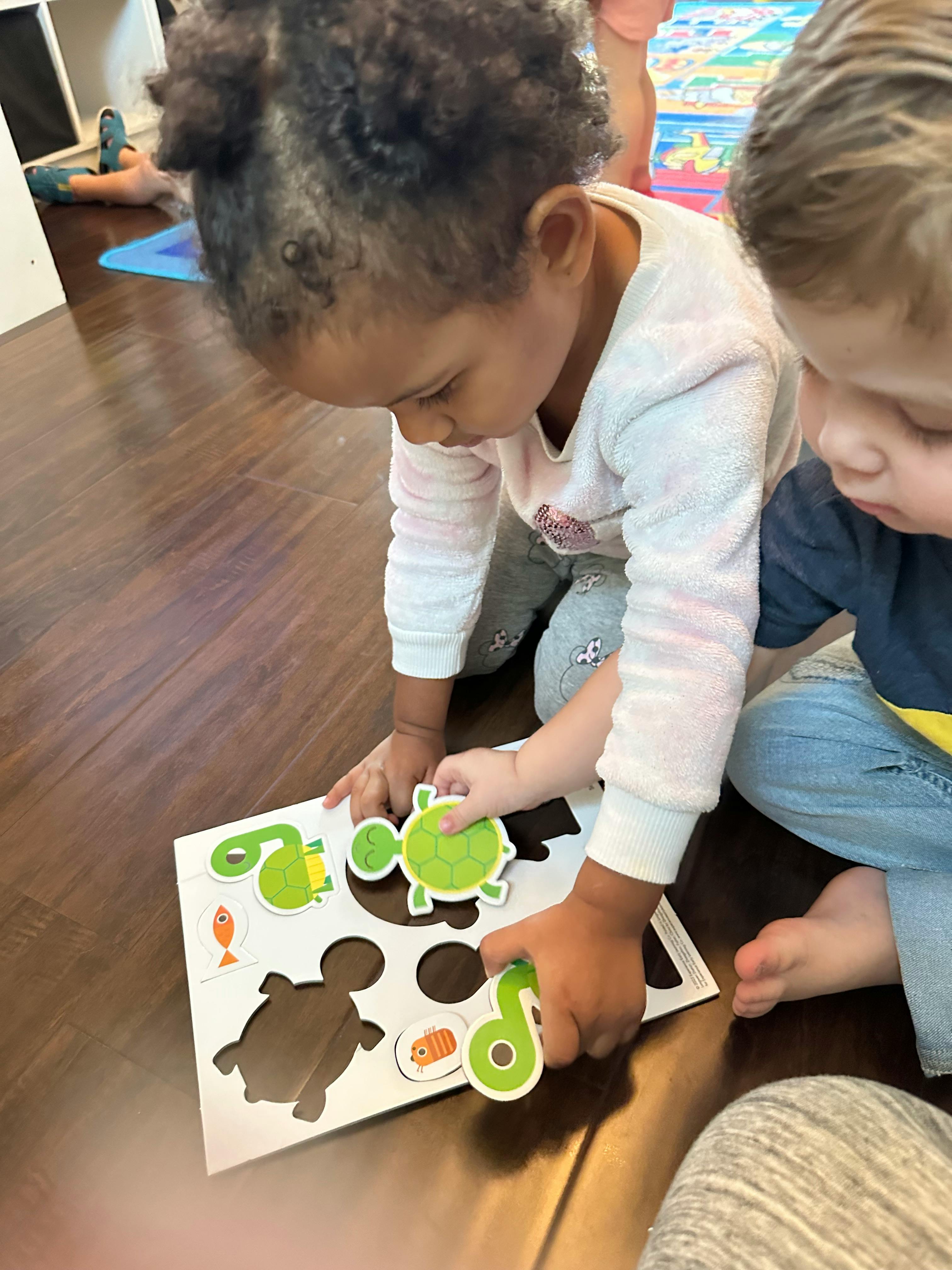 Two children playing with a turtle and number puzzle on the floor