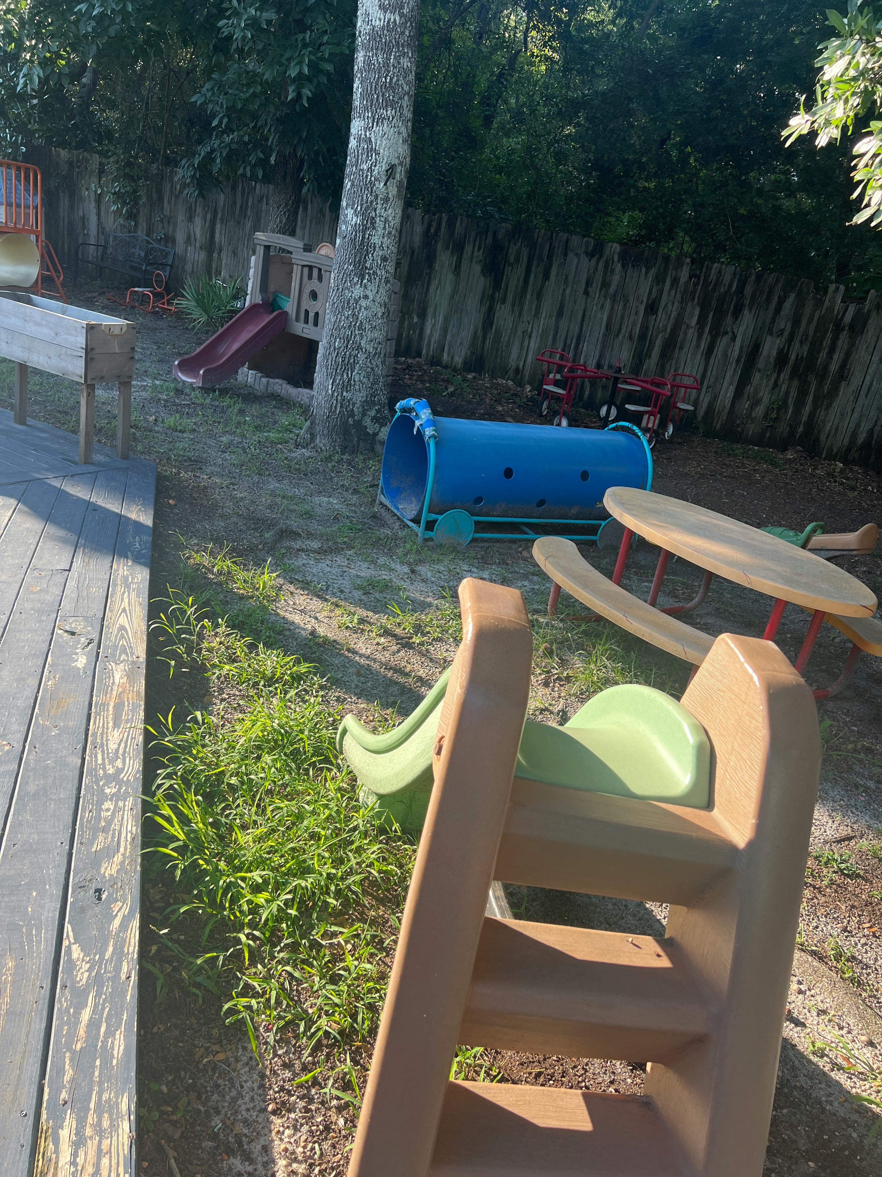 Playground with slides, a blue tunnel, and a wooden fence