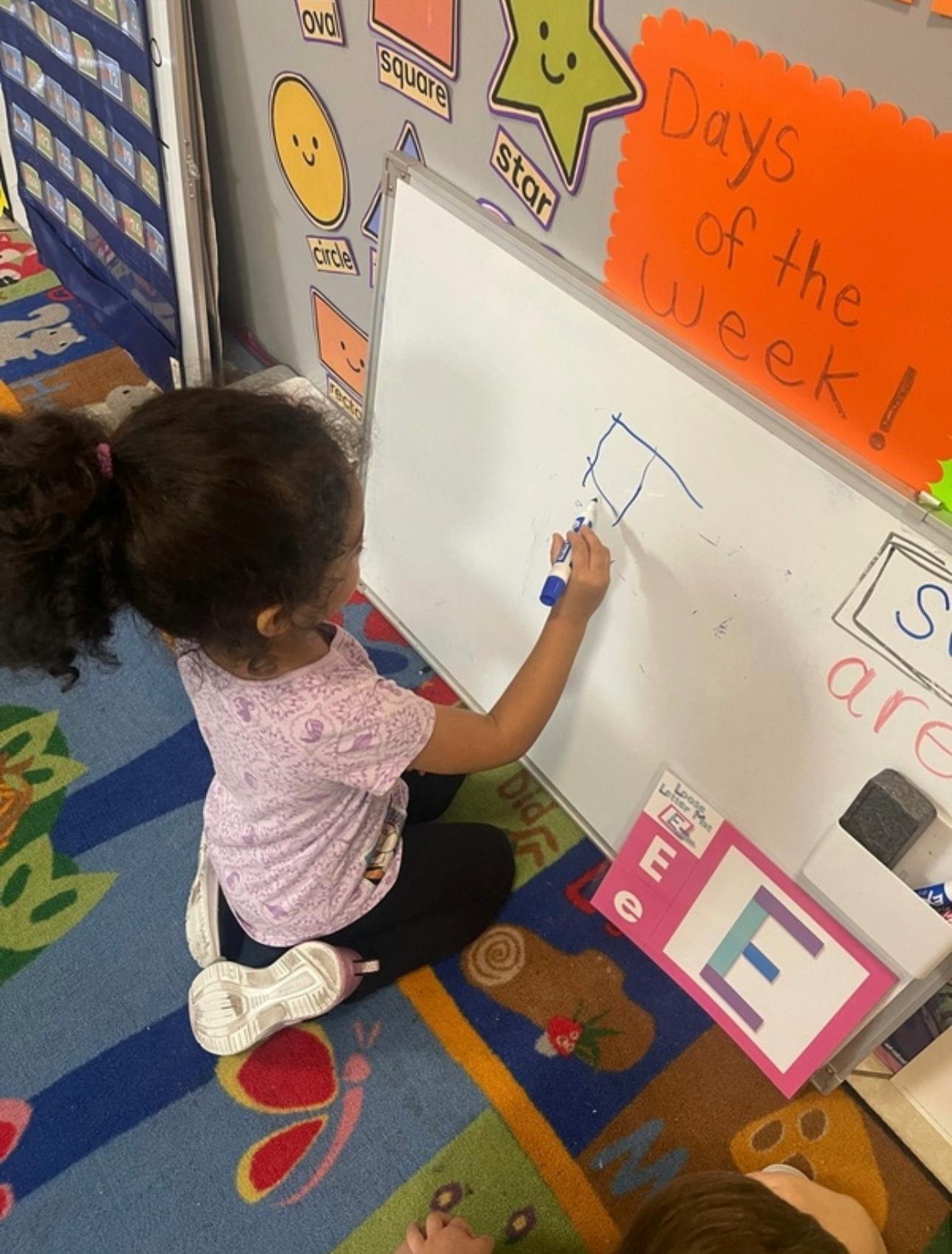 Child drawing on a classroom whiteboard