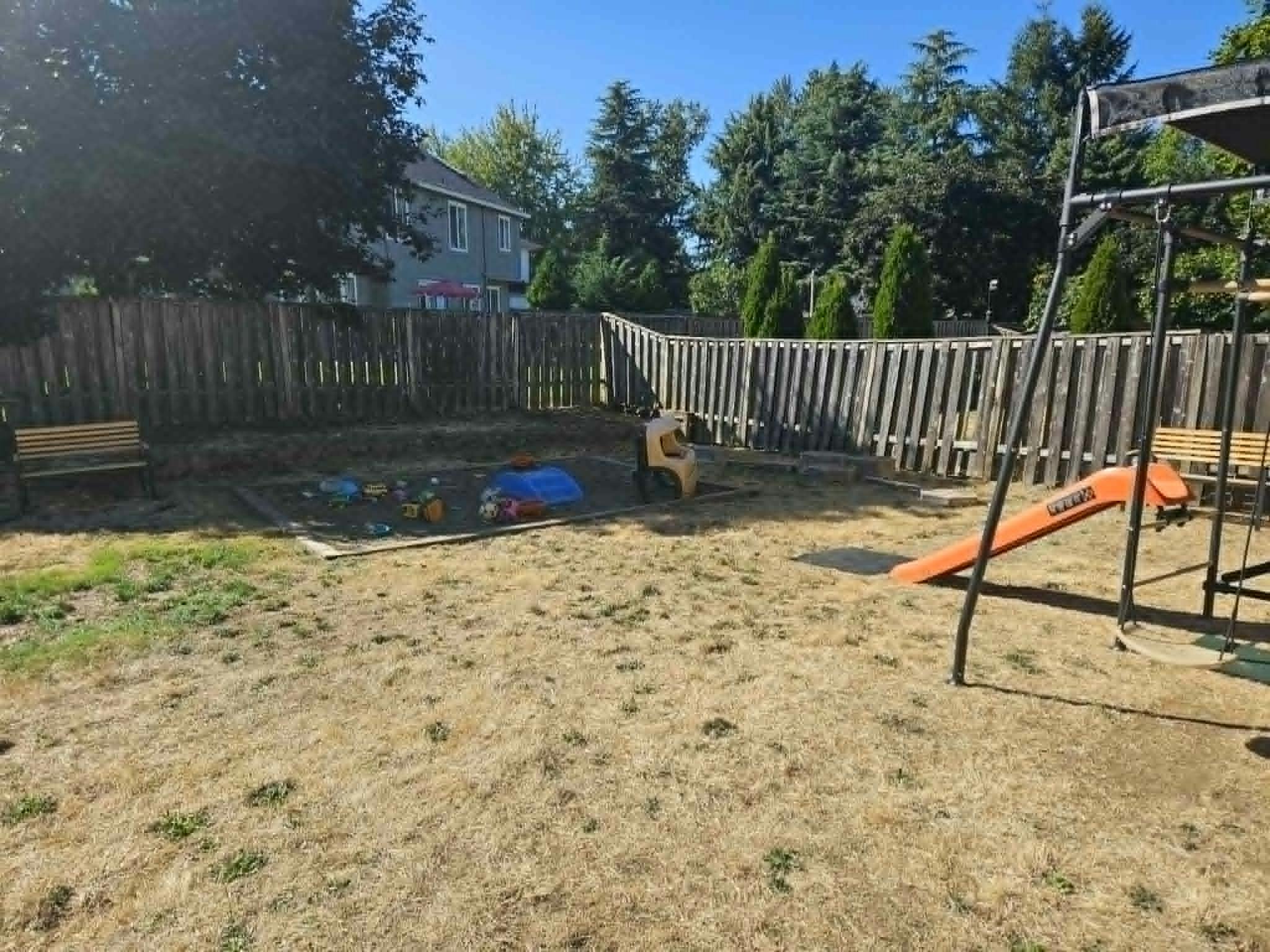 Backyard with a sandbox and a playset containing a slide