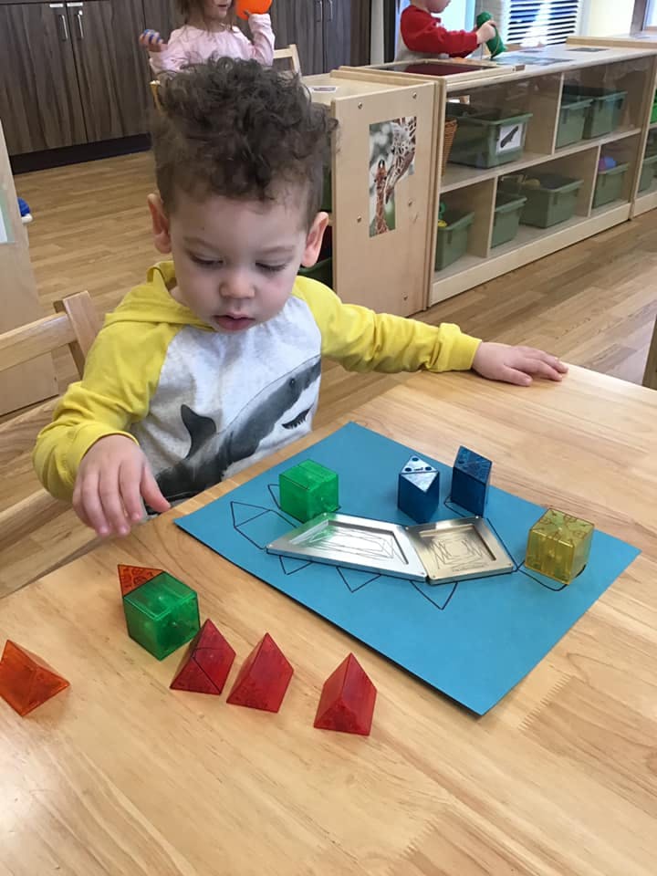 Child playing with geometric shapes on a table