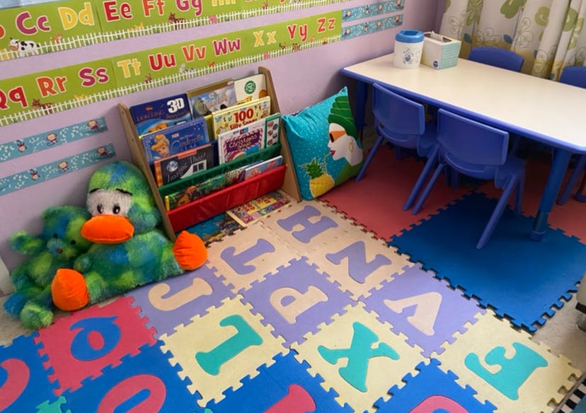 Classroom with alphabet floor mats, book display, and small table with chairs