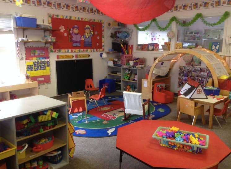 A colorful classroom with small tables, chairs, and play areas