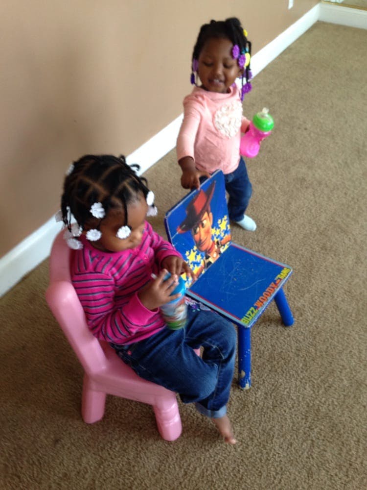 Two children playing with a small table and chair