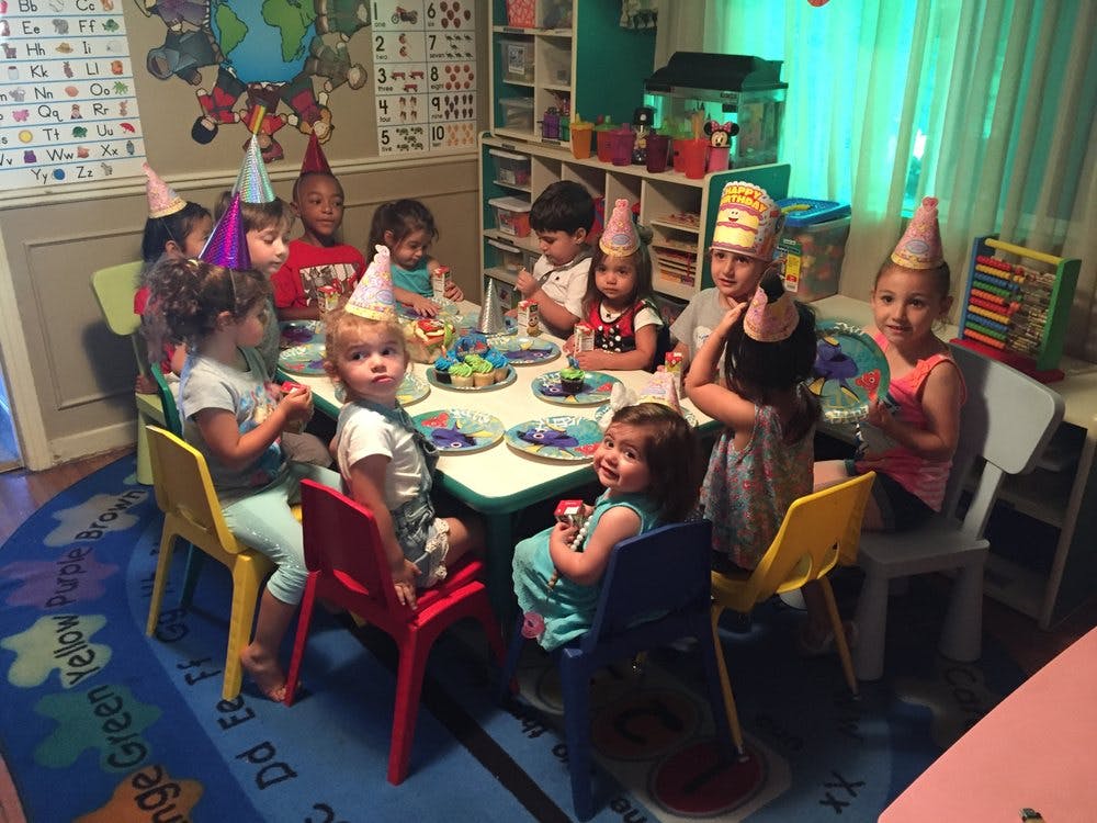 Children wearing party hats sitting around a table with plates