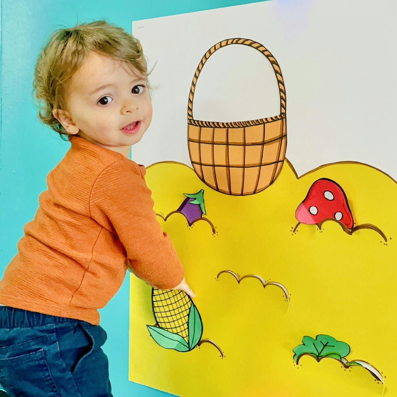 Child touching a harvest-themed educational poster on a wall