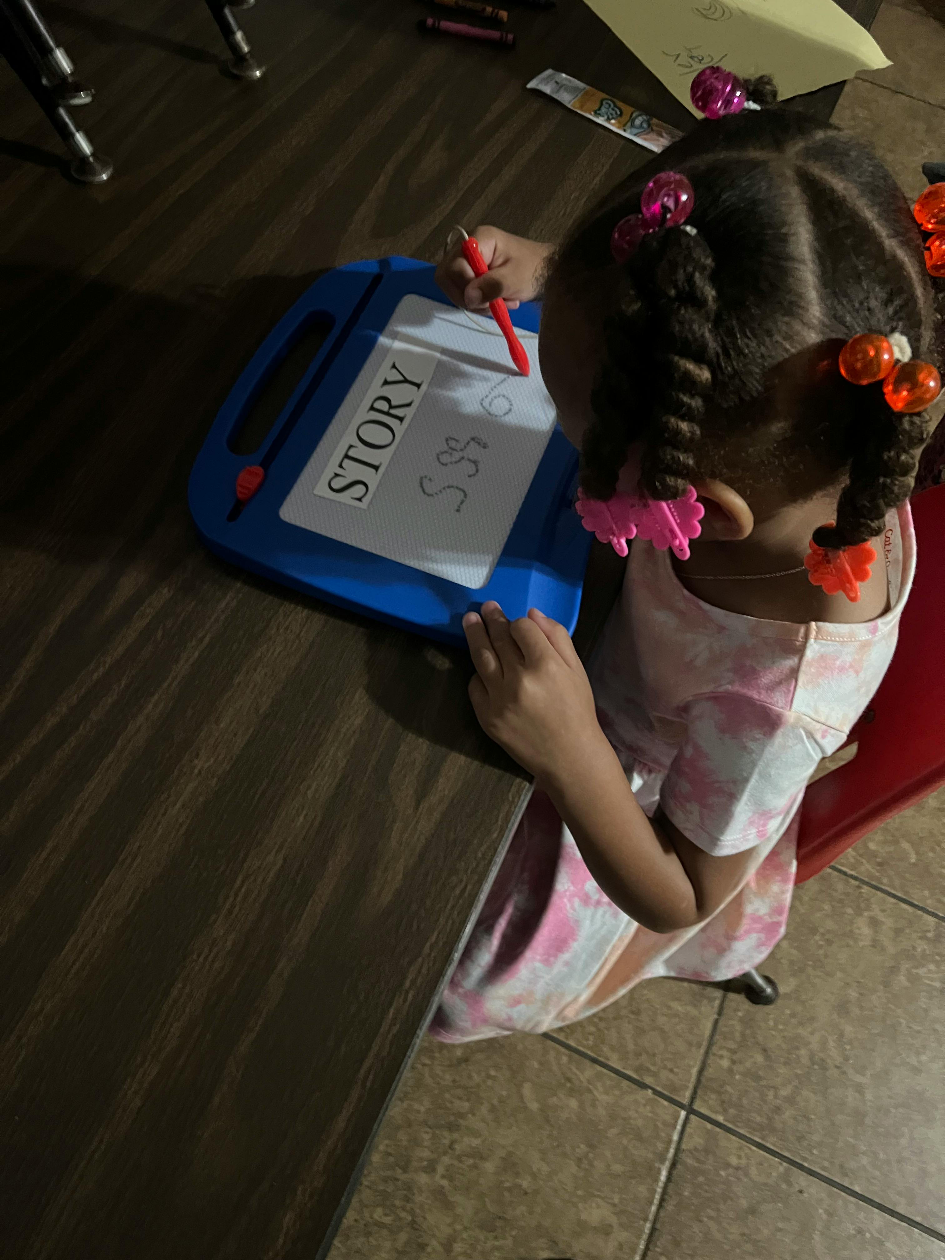 Child drawing on a magnetic board with the word "STORY" visible